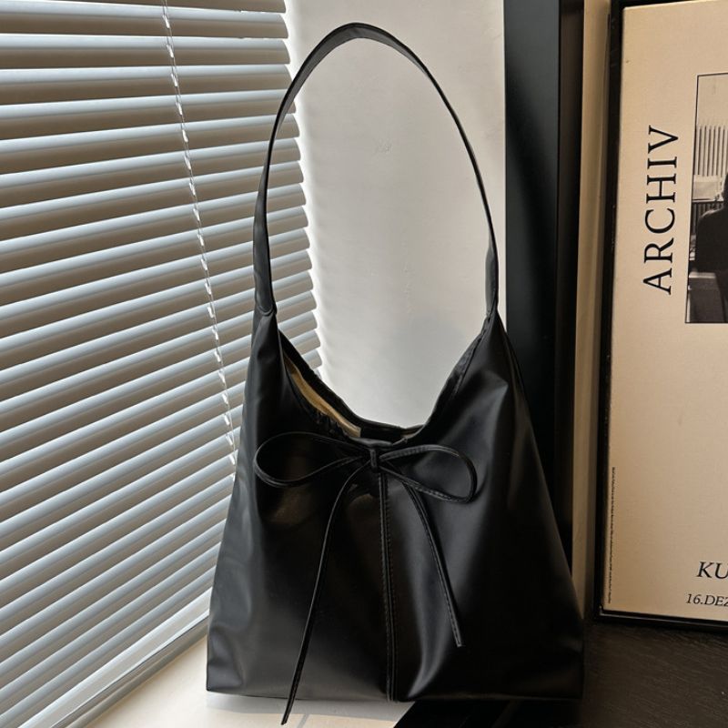 Black color ladies hand bag placed next to window