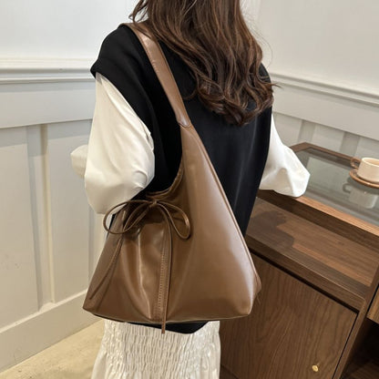 Person wearing a brown leather shoulder bag in an indoor setting.