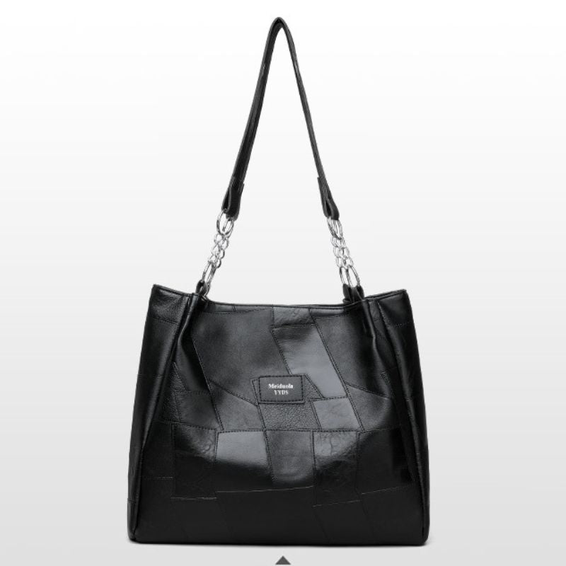 Black leather handbag with chain detail on a light gray background