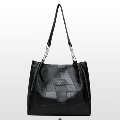 Black leather handbag with chain detail on a light gray background