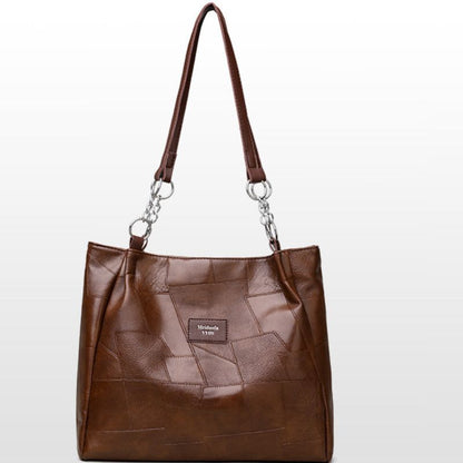 Brown leather handbag with a visible brand label on a white background