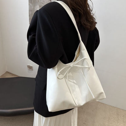 woman have white color soft leather hand bag or tote bag on her shoulder, wearing black color coat.
