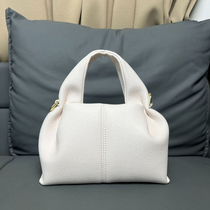 White handbag on a gray couch with pillows