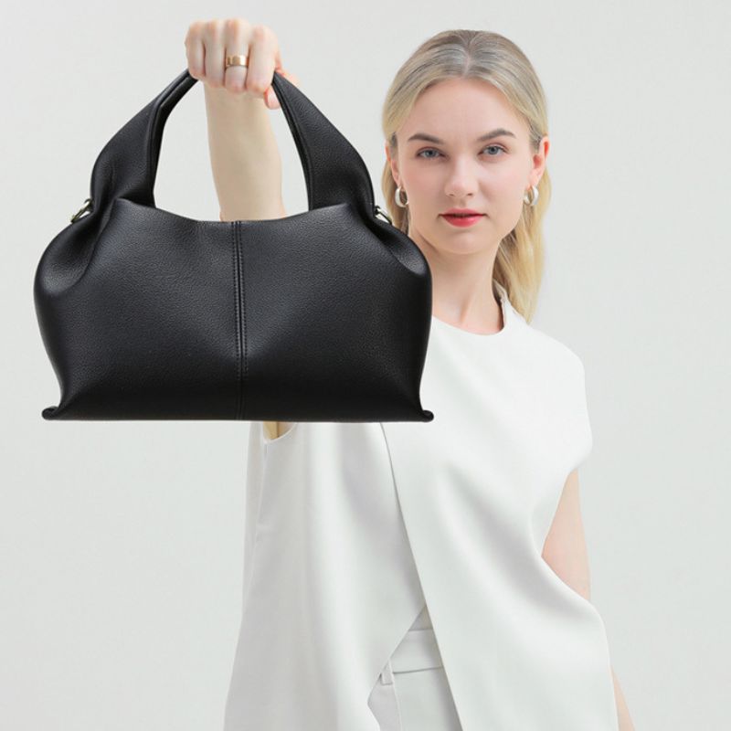 Woman holding a black handbag against a white background
