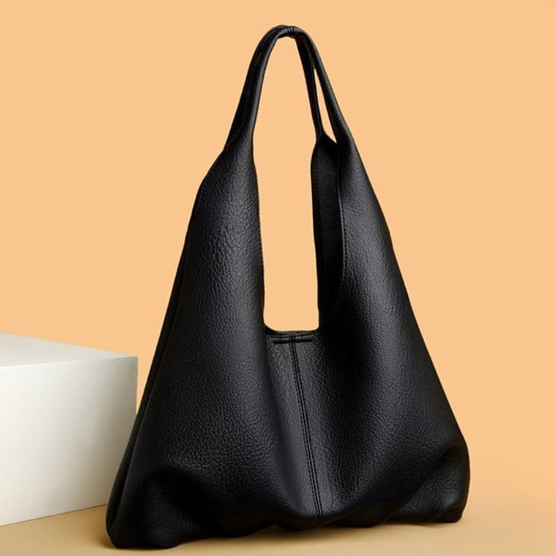 Black leather handbag on a beige background