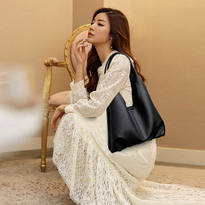 Woman in a white lace dress holding a black handbag in an elegant room.