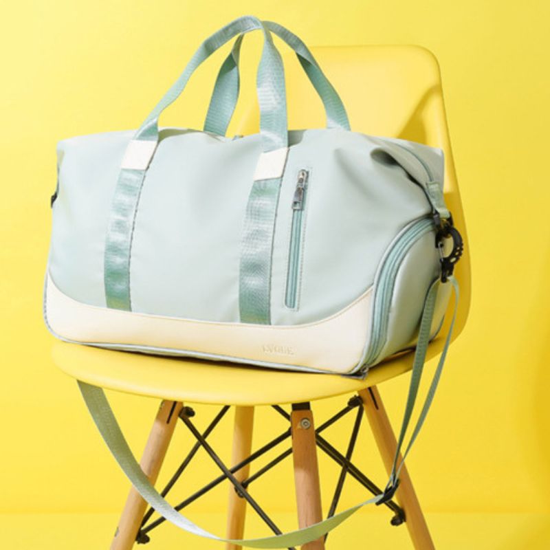 A green and beige duffle bag with a shoe compartment, placed on a yellow chair against a yellow background.