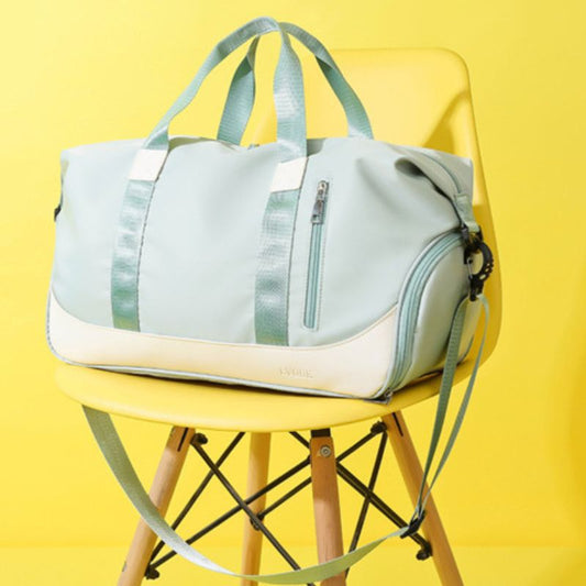 A green and beige duffle bag with a shoe compartment, placed on a yellow chair against a yellow background.