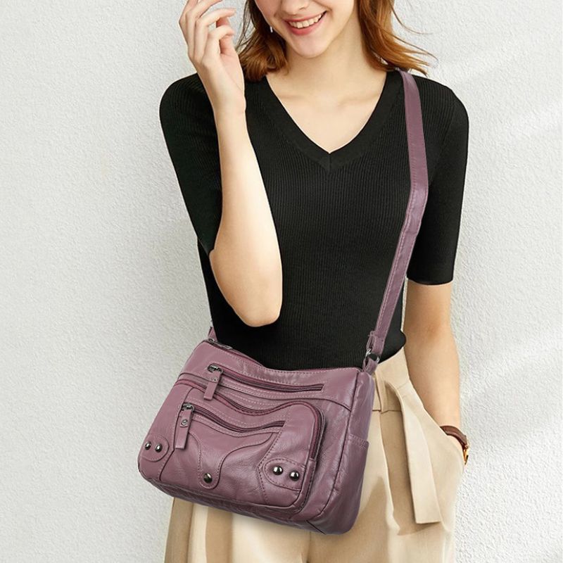 Woman carrying a purple handbag against a plain background