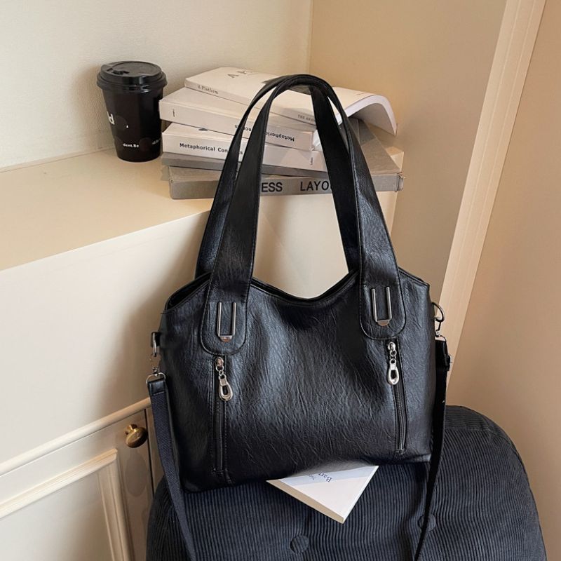 Black handbag on a chair with books and a coffee cup in the background