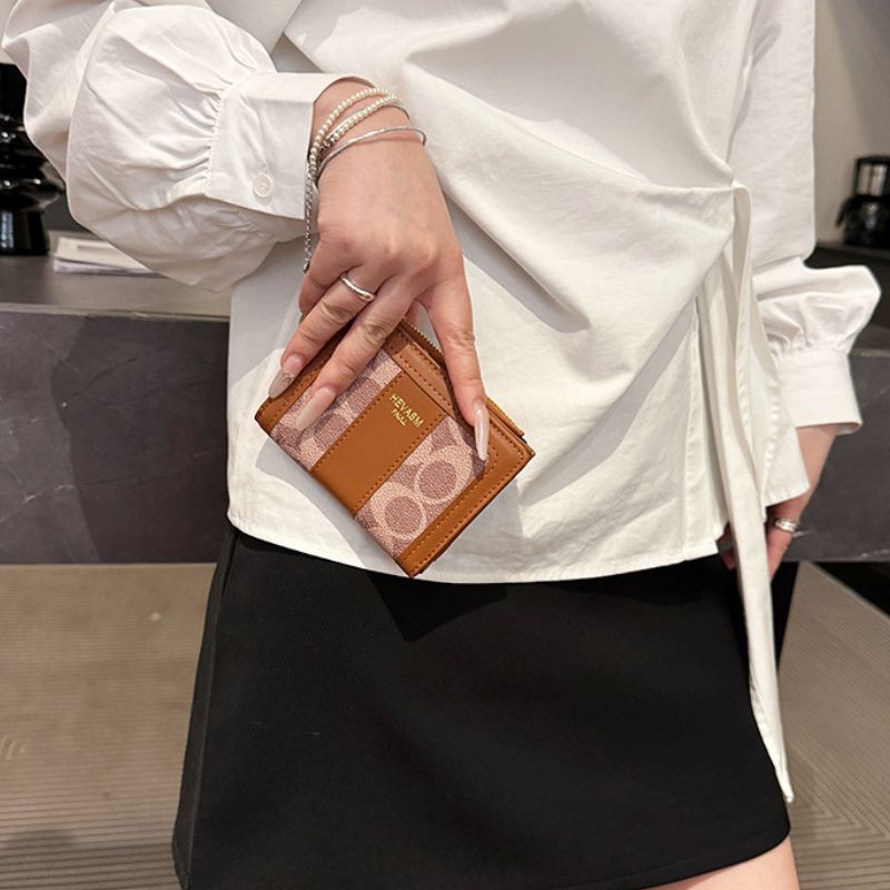 Person holding a brown wallet with a white shirt and black skirt