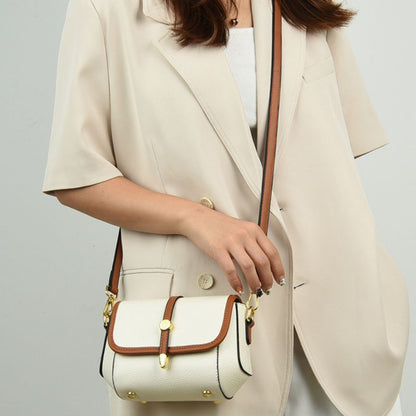 Person wearing a beige blazer holding a white handbag with brown accents.