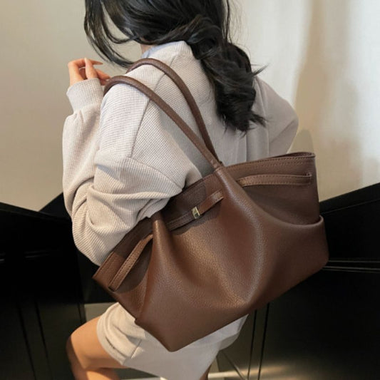 Woman hanging leather handbag tote bag on shoulders wearing a beige color cardigan