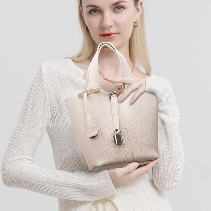Woman holding a beige handbag against a plain background