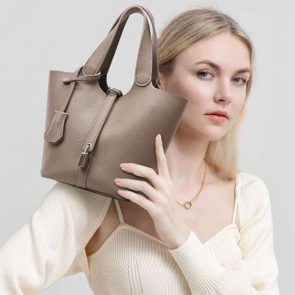 Woman holding a beige handbag against a light background