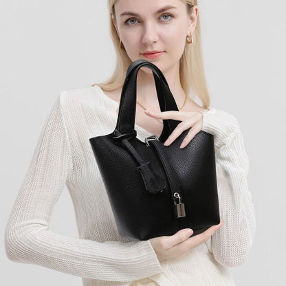Woman holding a black handbag against a plain background