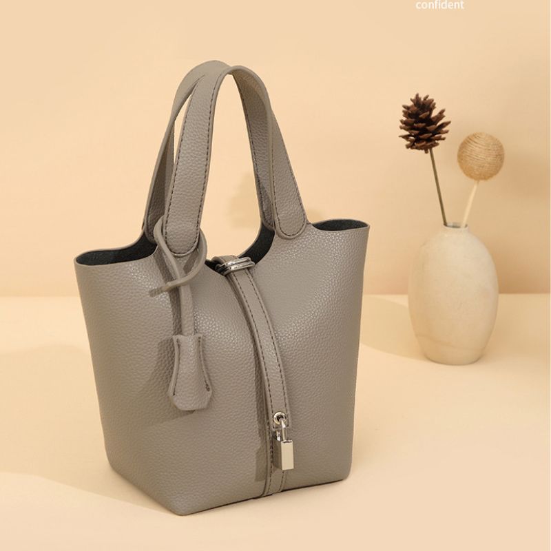 Gray handbag on a beige background with a vase and decorative items.