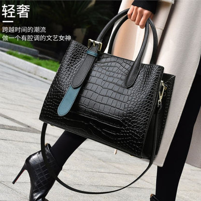 Black textured handbag with blue accents held by a person on a sidewalk.