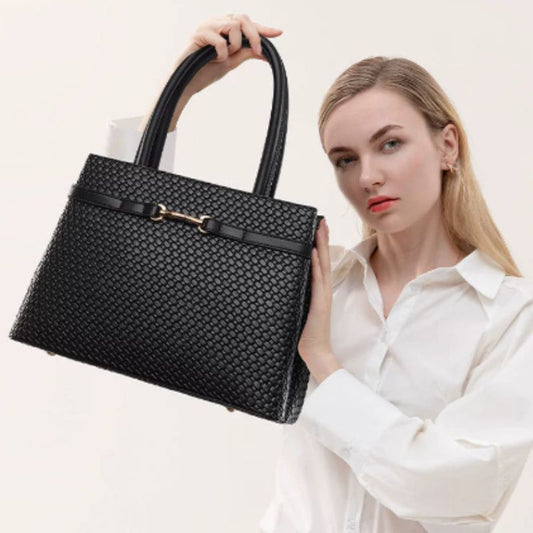 Woman holding a black woven handbag against a plain background